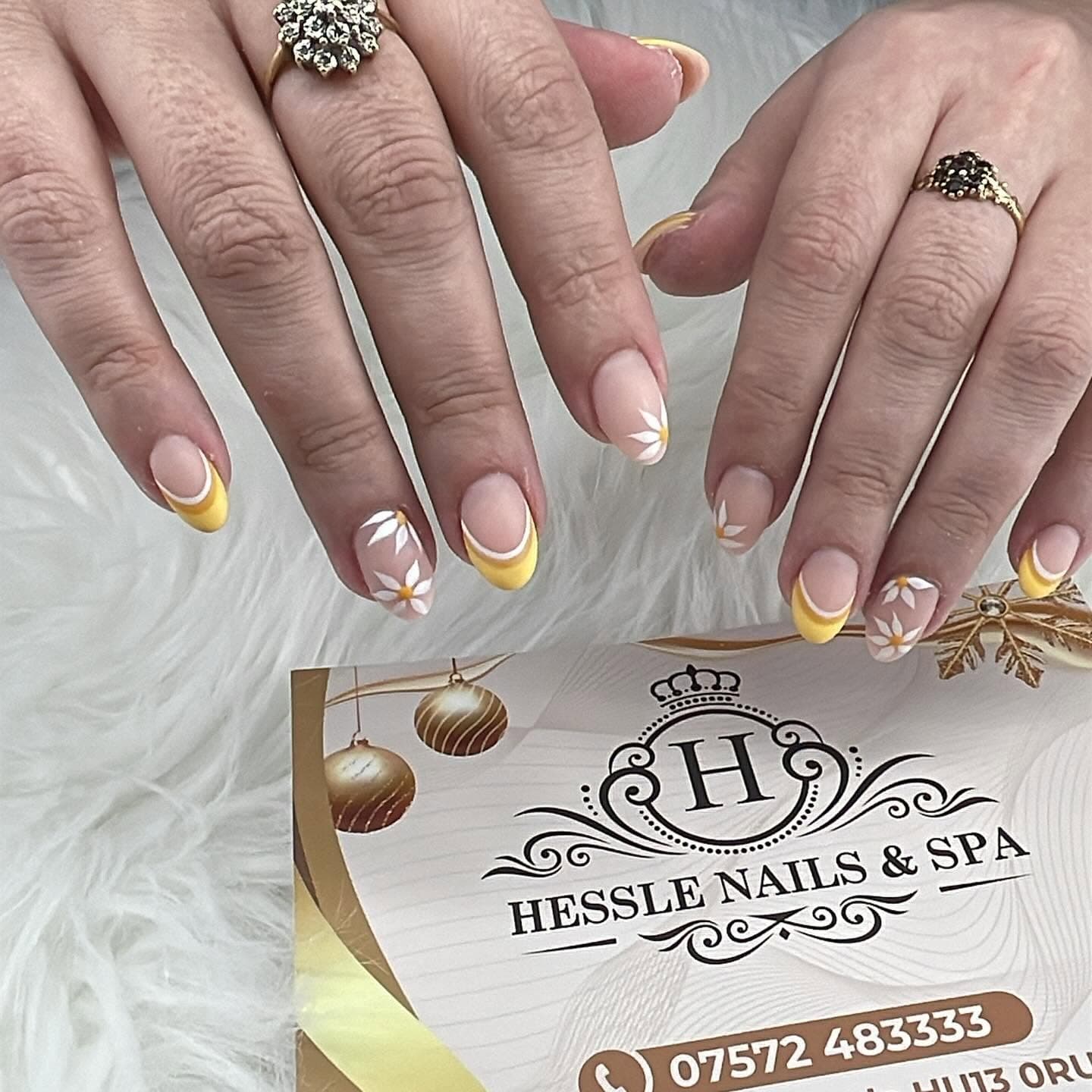Nude nails with yellow French tips and hand-painted daisies