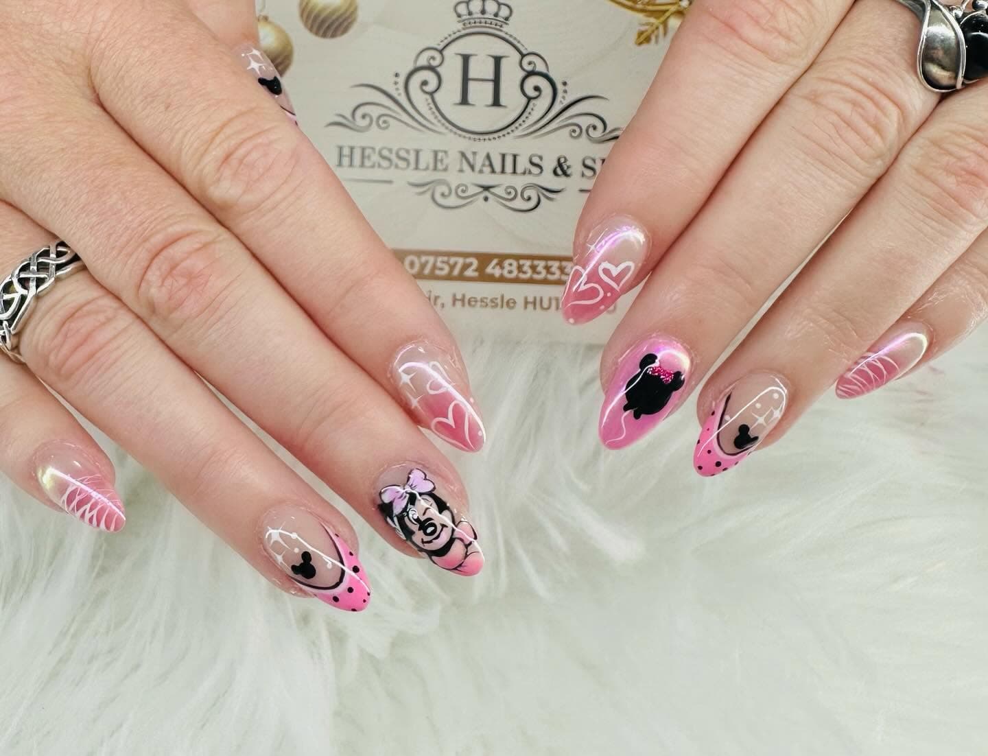 Pink Disney-themed nail art with hearts and character silhouettes